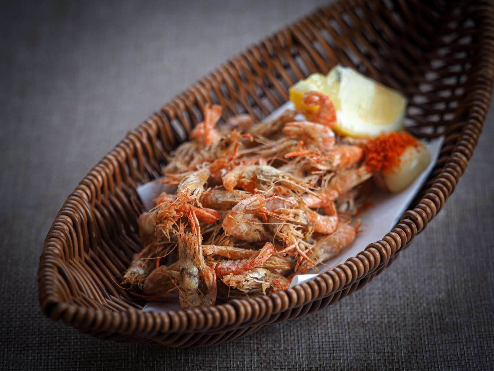 Crispy deep-fried baby shrimp in a basket with lemon, seafood food photography Singapore