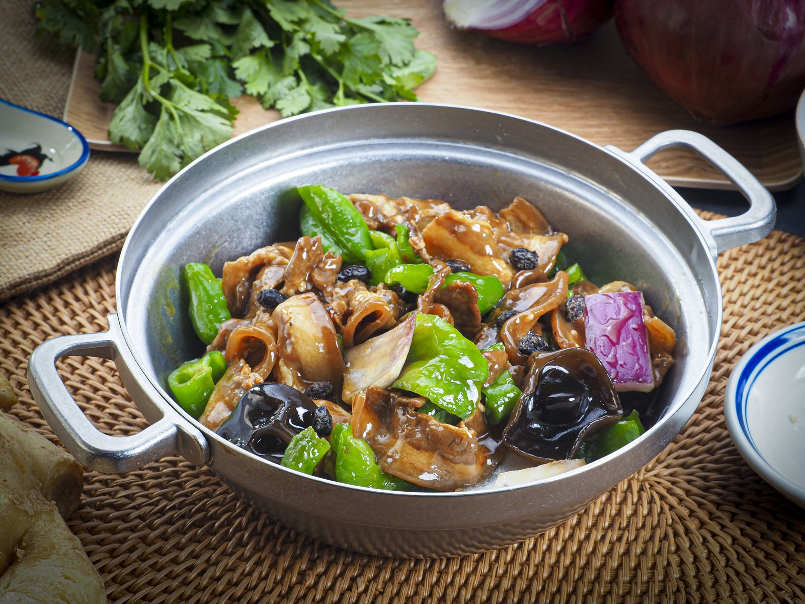 Stir-fried pork intestine with green pepper and black beans in a metal pot, Chinese food photography Singapore